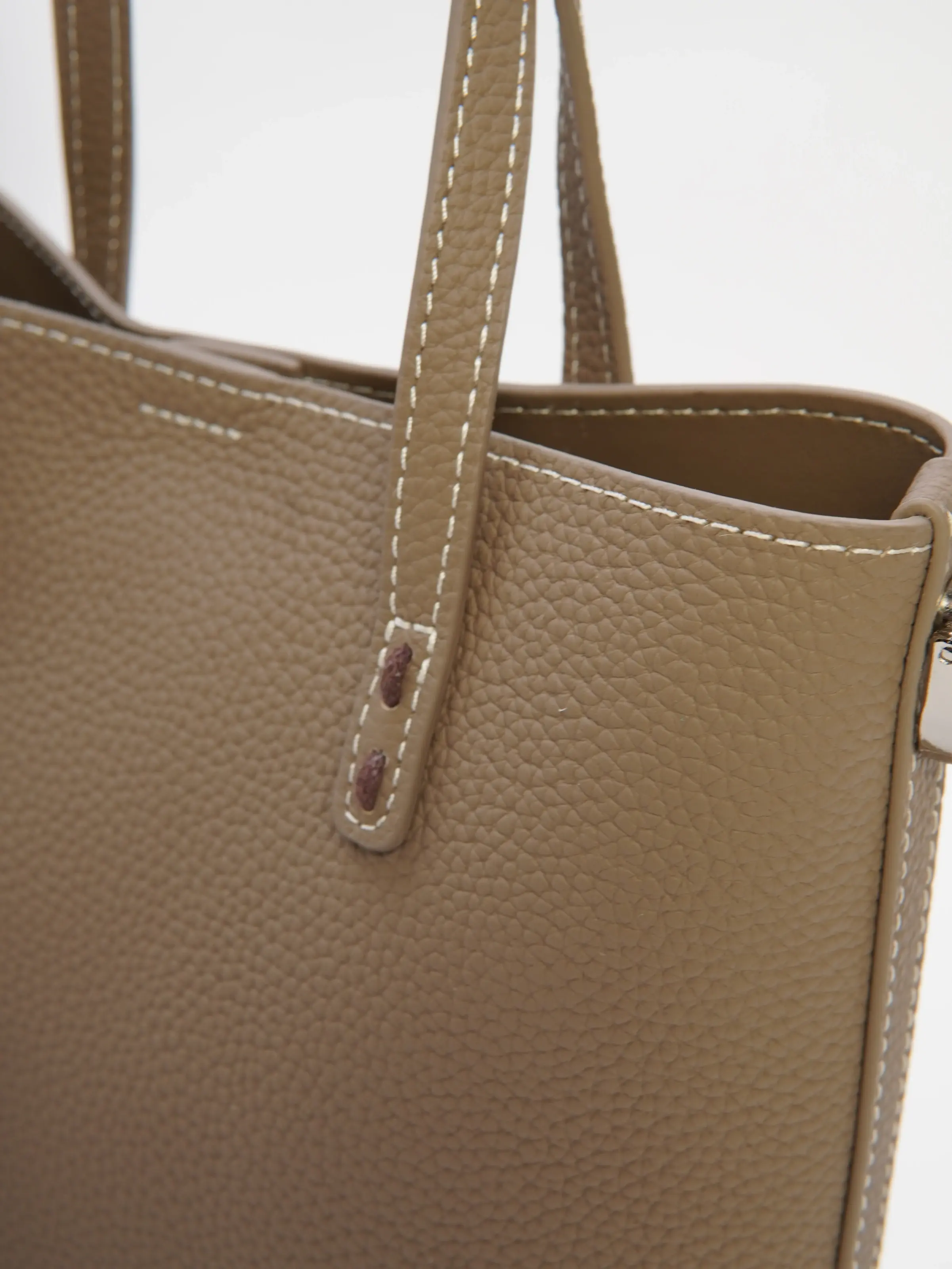 Close view of Lena taupe tote handles, top edge, and pebbled-look texture