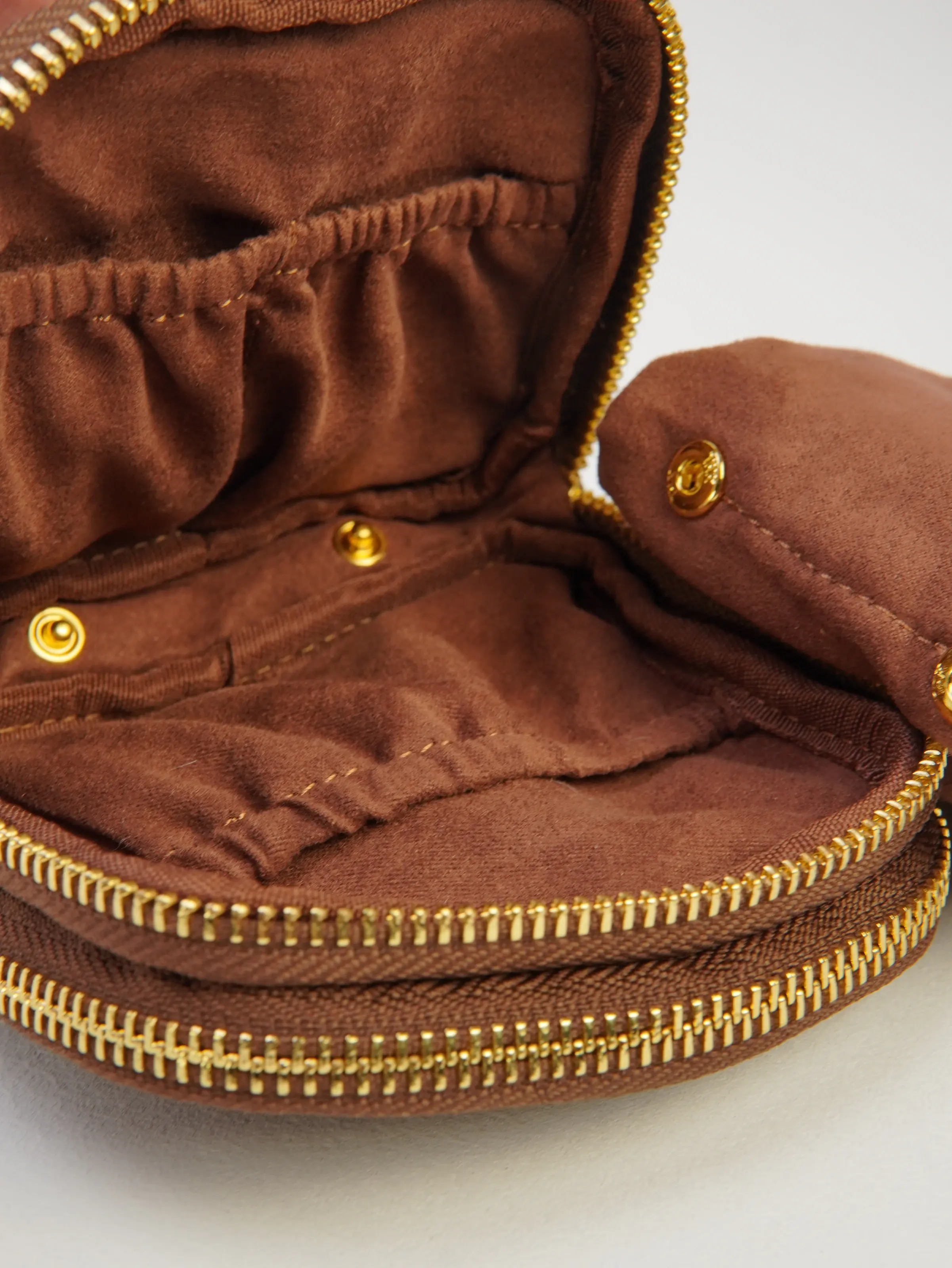 Close view of Nia jewelry case interior with gathered pockets and snap-tab details