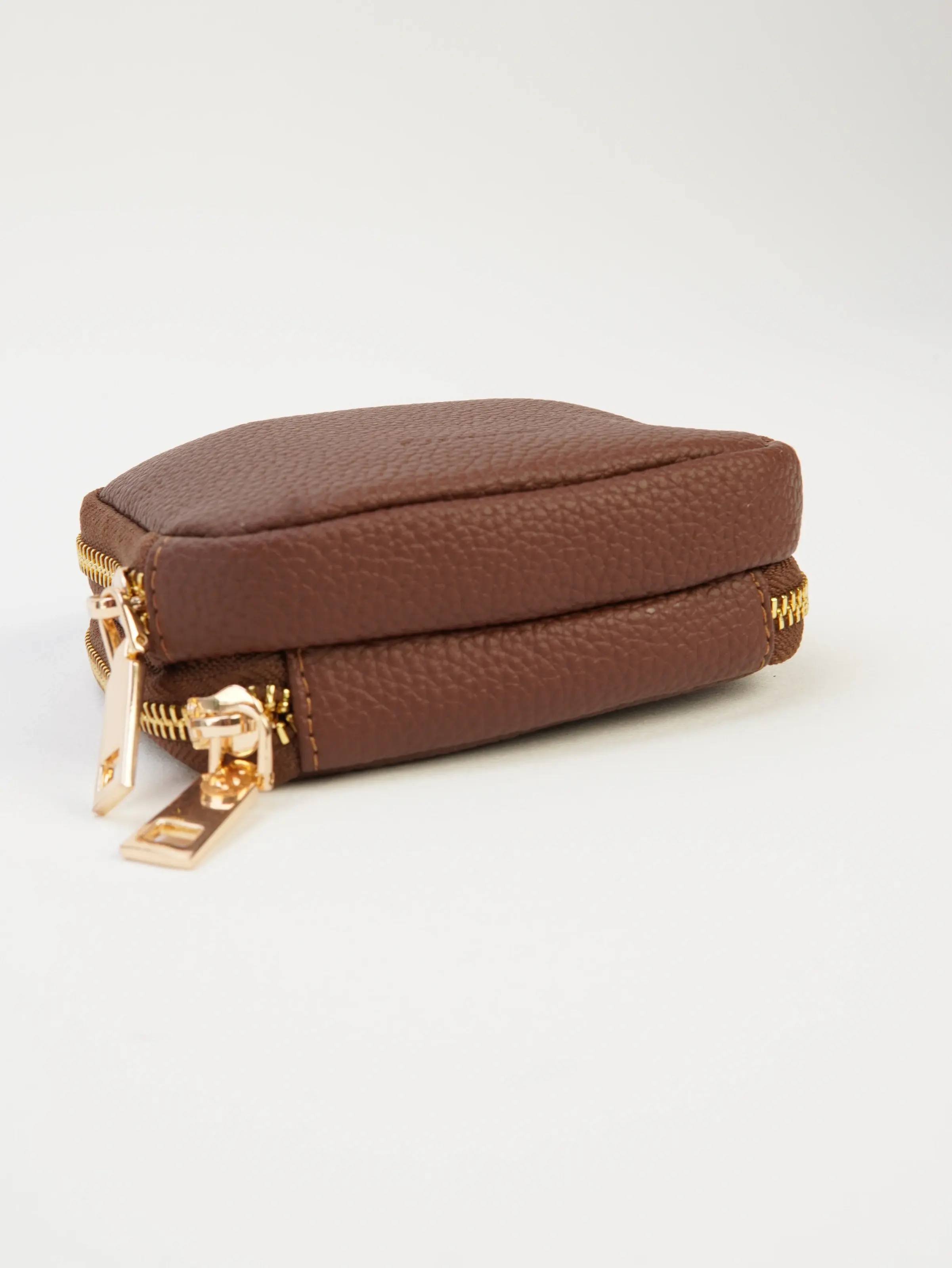 Side profile of the closed Nia jewelry case with two zip sections and a pebbled-look exterior